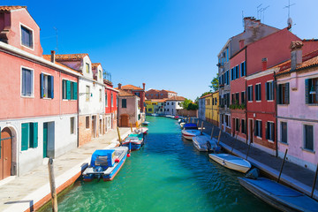 Fototapeta na wymiar Venice landmark, Murano island canal, colorful houses and boats during summer day with blue sky in Italy. Venice lagoon.