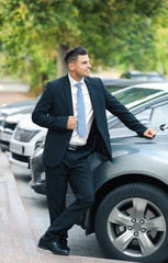 Attractive man in formal suit standing near car
