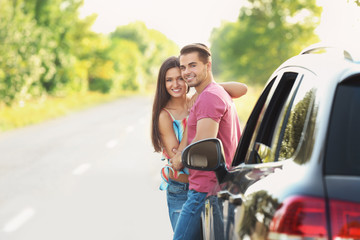 Beautiful young couple standing near car