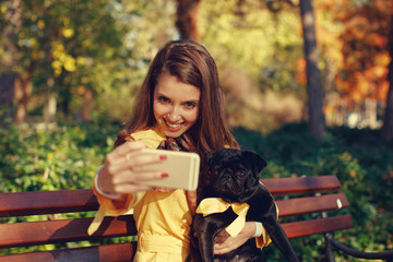 Young woman doing selfie with her pug dog in the park