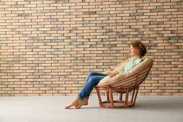 Young woman resting in lounge chair near brick wall