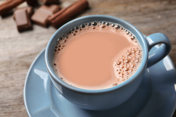 Cup with delicious cocoa drink on wooden background