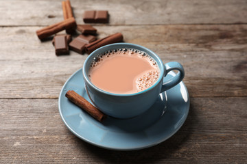 Cup with delicious cocoa drink on wooden background