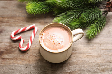 Mug with delicious cocoa drink on wooden background