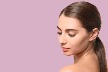 Young woman with eyelash extensions on color background