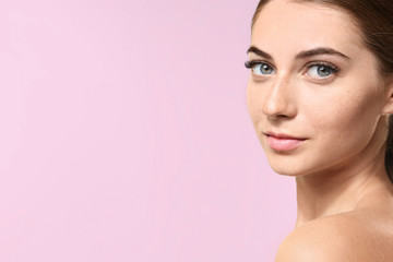 Fototapeta premium Young woman with eyelash extensions on color background