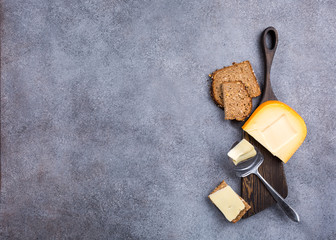 Delicious dutch gouda cheese with cheese slices, multigrain bread and special knife on old wooden board. Healthy food concept with copy space.