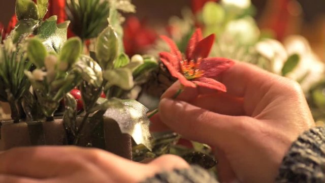 Female hands arranging christmas flower decorations in an oasis.
