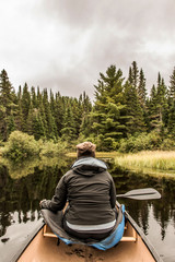 Girl canoeing with Canoe on the lake of two rivers in the algonquin national park in Ontario Canada on cloudy day