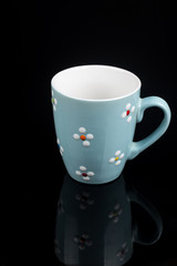 Blue coffee mug isolated above black background with reflections