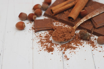 Broken Chocolate Pieces and Cocoa Powder on White Vintage Wooden Background