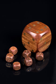 Brown wooden dices with dots isolated above black background wit