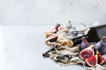 Bottle, corkscrew, glass of red wine, figs on a table