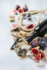 Bottle, corkscrew, glass of red wine, figs on a table