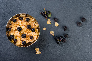 Cornflakes cereals with berries on dark background, flat lay