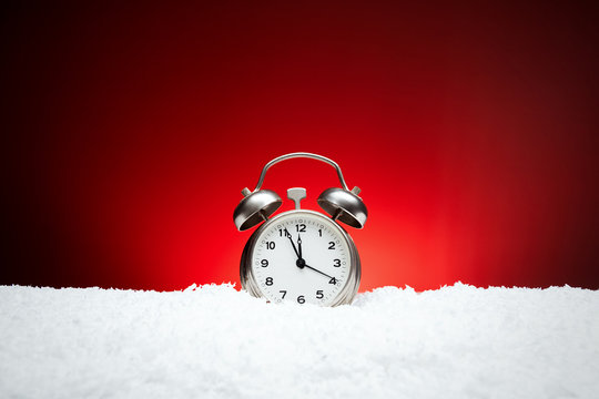 Christmas composition. Greeting card for new year clock Alarm clock on snow on red background with place for congratulatory text