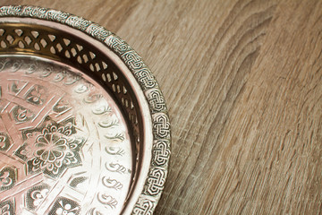Close up of moroccan shiny tea plate on a wooden table