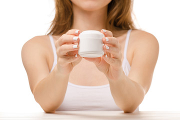 Beautiful woman sits a jar of hand cream