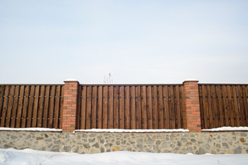 Wooden fence covered by snow after winter blizzard