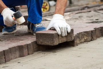 Laying Paving Slabs by mosaic close-up. Repairing sidewalk. Workers laying stone paving slab. laying of paving slabs by a professional master builder in blue overalls