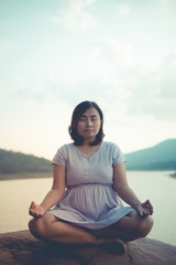 Fototapeta na wymiar Pregnant woman sit on the rock for play yoga side dam,vintage style,pastel tone,dark,film