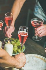 Holiday celebration table setting with food. Friends hands eating and drinking together. People having party, gathering, celebrating with rose champaign