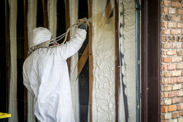 Worker spraying closed cell spray foam insulation on a home that was flooded by Hurricane Harvey