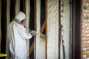 Worker spraying closed cell spray foam insulation on a home that was flooded by Hurricane Harvey - obrazy, fototapety, plakaty