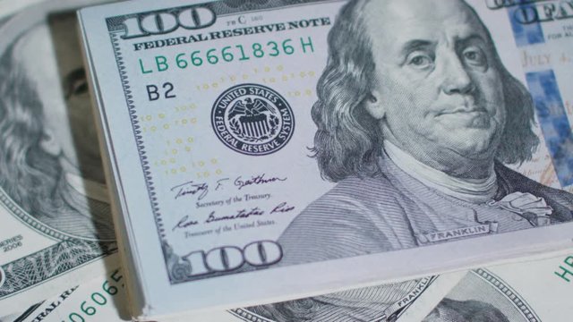A pile of hundred dollar banknotes on a table. Close-up shot
