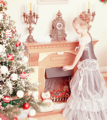The little girl warms his hands around an electric fireplace.