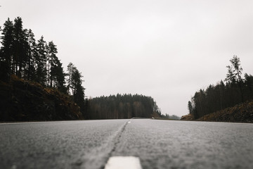 Asphalt road in the middle with a light fog in the rainy weather low shot. A low angle shot at the middle of an empty road.