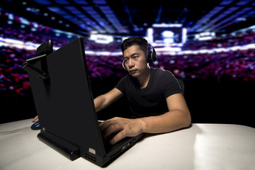 Competitive asian male professional E Sports video gamer playing an FPS, or MMO game on a computer and streaming online.