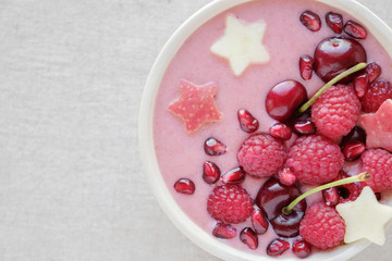 red pink smoothie bowl with cherry, strawberry, raspberries and pomegranate