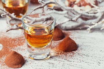 Whiskey or liqueur, truffle chocolate candies in cocoa powder and christmas decorations on white...
