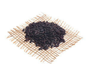 Black Rice. Grains over hessian fabric, isolated white background.