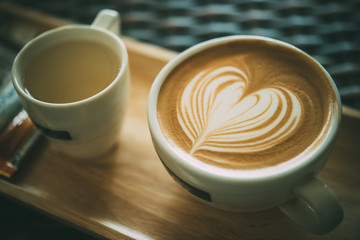 Close up latte art on wooden plate in coffee shop vintage style,selective focus