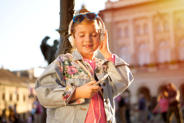 Pretty  young girl listening music with her headphones in the street