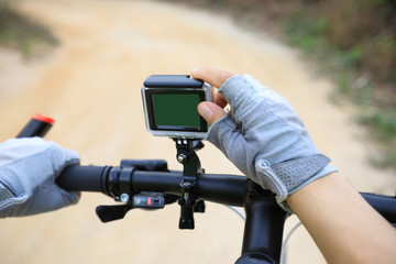cyclist hands set the action camera mounted on mountain bike