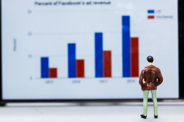 Miniature people : small figures businessmen stand and look at the graph on the phone display with copy space and using as background finance business team competition concept.