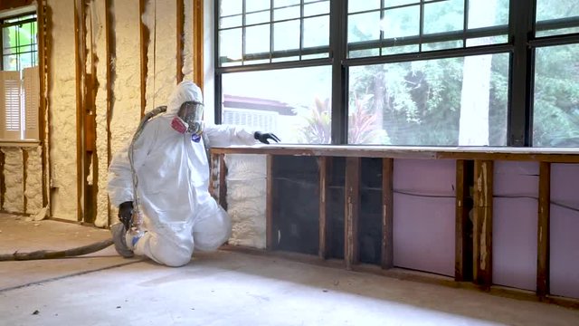 Worker spraying closed cell spray foam insulation on a home that was flooded by Hurricane Harvey