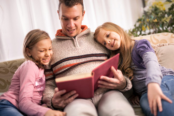 happy family father and children reading a book