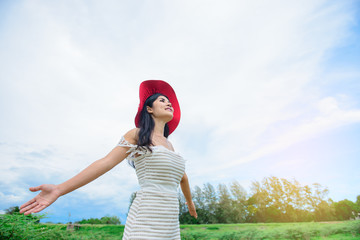 Asian woman wear red hat stretching arms breathing fresh air at mountain with beautiful sky