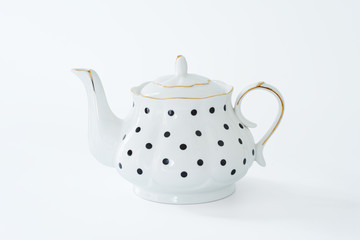 White teapot with black dot design isolated on white background .