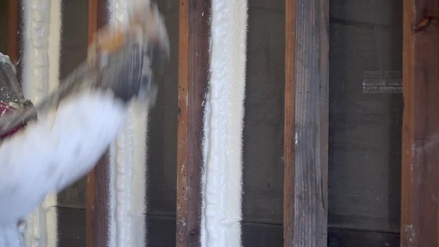 Worker spraying closed cell spray foam insulation on a home that was flooded by Hurricane Harvey