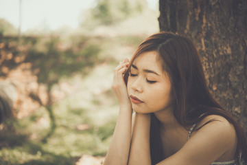 Naklejka premium Close up asian sad woman sit under the tree vintage style,heartbreak girl concept