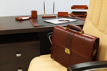 leather briefcase on beige chair next to office desk