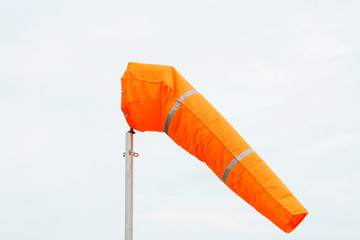 windsock on cloudy sky background in windy weather indicate the local wind direction (also called:...