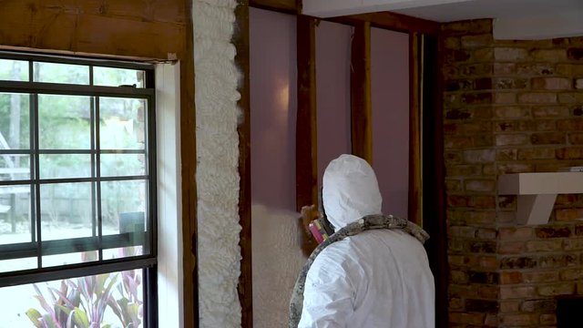 Worker spraying closed cell spray foam insulation on a home that was flooded by Hurricane Harvey