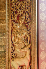 Fototapeta na wymiar Art Craft of Devas on the door in Wat Xiengthong, Luang Prabang, Laos.