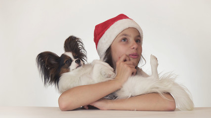 Beautiful teenage girl in Santa Claus hat happily hugs her dog and look surprised on white background